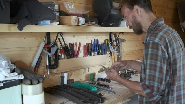 Bearded man joiner woodworker choosing construction carpentry tools in his workshop. DIY concept.