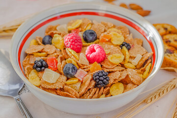 Healthy breakfast. Sunlight, dry muesli, spikelets, candied fruits and ripe summer berries. Close-up, top view. On a white background. Selective focus.