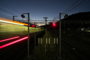 Fototapeta na wymiar A train passing a station at dusk in Kyoto 