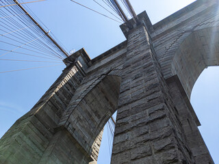 Obraz premium Looking up at arches in Brooklyn Bridge in New York on sunny summer day