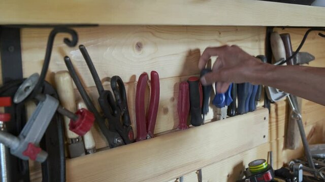 Close up woodworkers hands chooses construction carpentry tools in workshop. DIY concept.