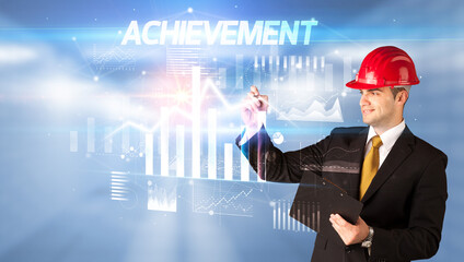 Handsome businessman with helmet drawing ACHIEVEMENT inscription, architecture business plan concept