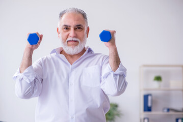 Aged male employee doing physical exercises during break