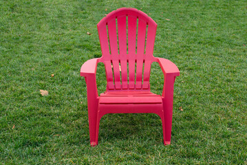 One red wooden plastic chair standing on green grass