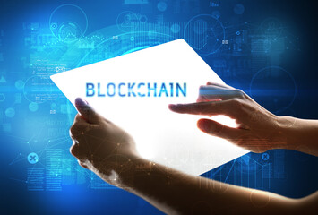 Hand holdig futuristic tablet with BLOCKCHAIN inscription, new technology concept