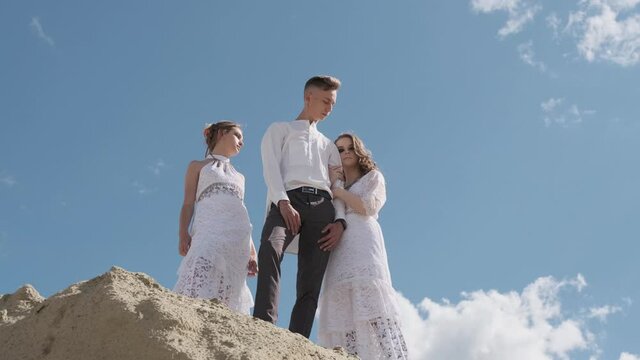 A love triangle, a man posing with two young girls in white dresses, friendship, the concept of polygamy.