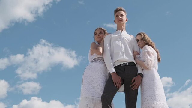 A love triangle, a man posing with two young girls in white dresses, friendship, the concept of polygamy.