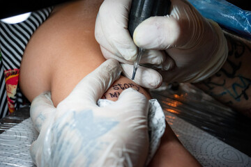 Realizando tatuaje en brazo femenino - obrazy, fototapety, plakaty