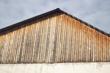 Fototapeta premium The roof of the building. Plank roof on concrete fittings. Old house. Blank wall. Ridge roof type.