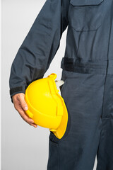 Worker standing in blue coverall holding hardhat - 396026611