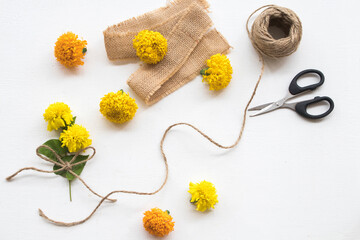 marigold yellow flowers on sack ,scissors ,rope arrangement flay lay postcard style on background...