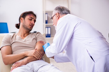 Obraz premium Young face injured man visiting experienced male doctor traumato