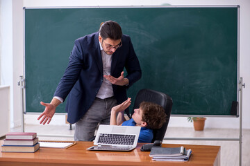 Young male teacher and schoolboy in the classroom