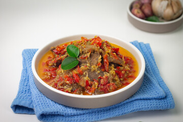 Dendeng Balado, Indonesian traditional beef cuisine from Padang, West Sumatra with slices beef cooked with some spices and a lot of chilies. Served on ceramic plate and isolated white background.   