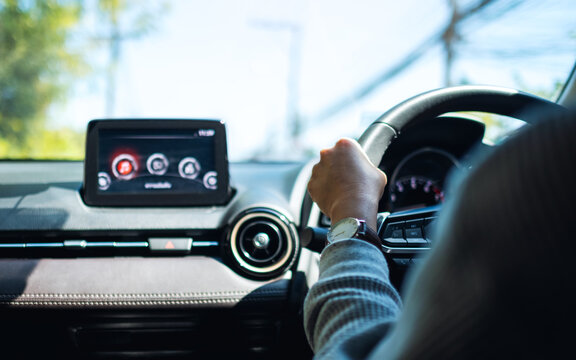 Closeup image of a woman holding steering wheel while driving a car on the road