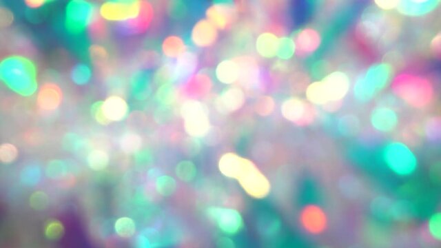 Festive blurred holographic iridescent spectrum colors lights. Holiday background of abstract glitter bokeh with multiple colors. Blue pink purple neon pastel gradient of diamonds