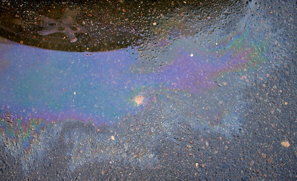 Colorful gas stain on wet asphalt. Oil stain caused by a leak under a car