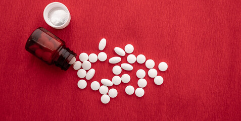 Medical concept, white pills on red background.
