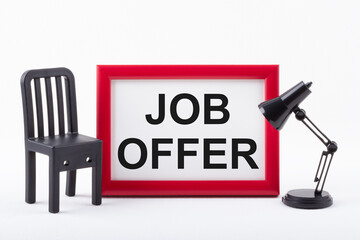Text JOB OFFER in red frame next to a miniature chair and lamp on white background. Business...