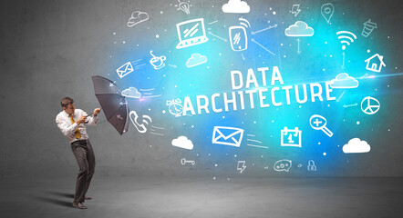 Businessman defending with umbrella from DATA ARCHITECTURE inscription, modern technology concept