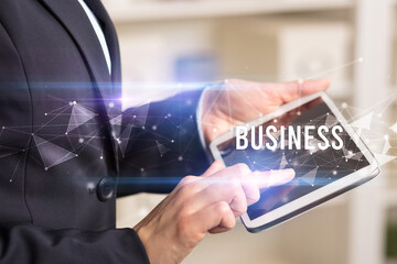 Close up hands using tablet with BUSINESS inscription, modern business technology concept
