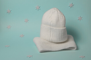 Warm knitted women's clothes on a blue background with snowflakes.