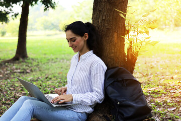 Beautiful young woman working and playing laptop in the garden park.