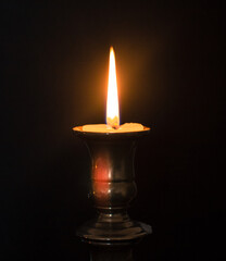 A burning candle in a candle stand
