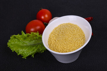 Raw couscous in the bowl served salad leaves, tomato and pepper