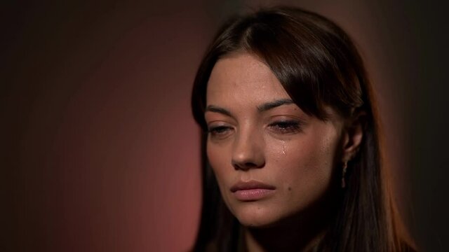 charming woman is crying, closeup of face in studio, sadness and sorrow, tears on cheek