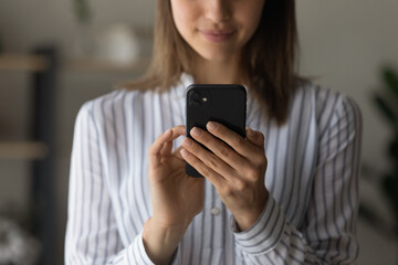 Fototapeta premium Crop close up of woman use smartphone gadget texting or messaging online. Female hold cellphone browse surf wireless internet on device, shopping online. Technology, communication concept.