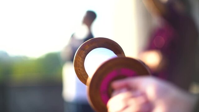 slow motion shot of thread being pulled quickly from charkhi spool as an out of focus person in the background flies the kite and takes the kite higher and farther