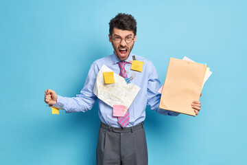 Indoor shot of angry man office worker shouts at colleagues wears formal shirt with tie grey...