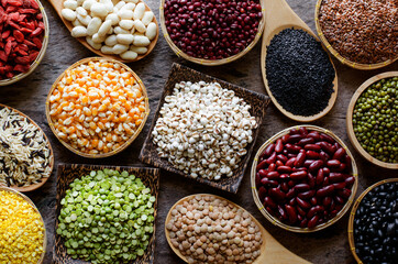Variety kinds of natural cereal and grain seeds in wooden equipment on grunge background in dark tone