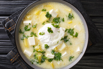 Traditional Venezuelan breakfast of chicken broth, with potatoes, eggs, cheese and cilantro close-up in a bowl on the table. horizontal top view from above