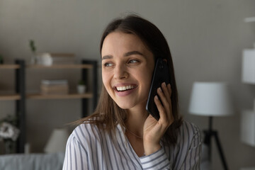 Overjoyed millennial woman look in distance enjoy talking speaking on cellphone gadget using mobile provider connection. Happy young Caucasian female have pleasant smartphone call on device.