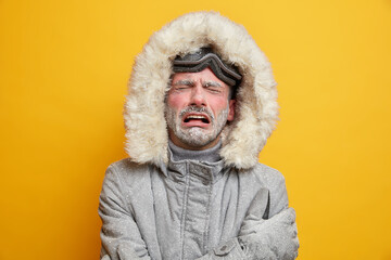 Stressed cold man cries from despair has displeased face expression frozen face covered with...