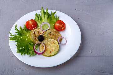 White plate with grilled stalks with cherry tomatoes on lettuce leaves on a concrete background.