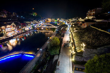 View of illuminated at night riverside houses in ancient town of Fenghuang known as Phoenix, China