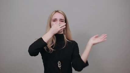 Covering nose with hand showing something stinks, isolated, hands face against, staring into the camera, eyes wide open, two fingers. Pinches snout looks, disgust bad smell sign. Attractive woman