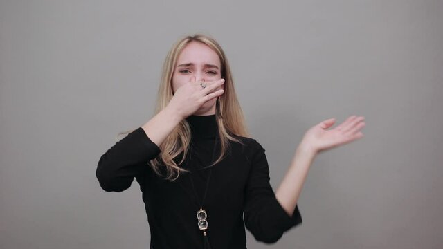 Covering nose with hand showing something stinks, isolated, hands face against, staring into the camera, eyes wide open, two fingers. Pinches snout looks, disgust bad smell sign. Attractive woman