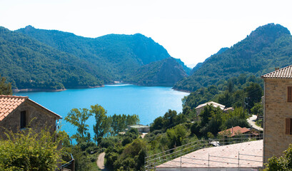Fototapeta na wymiar Lac de Tolla and the mountain village of the same name. Deep green trees surround the blue lake with its crystal clear water. Corsica France