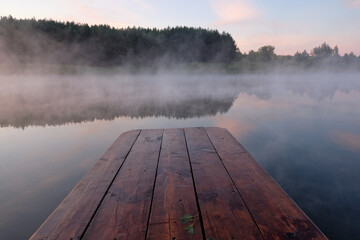 Summer, lake, early morning, beautiful sky, fog over the water. A wooden dock.
