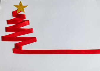 Red Christmas tree made with red ribbon and golden star and christmas bells on white background.