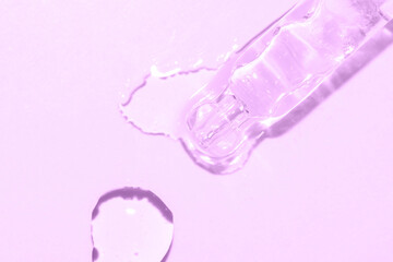 close up macro of pipette dropper with liquid on a purple background