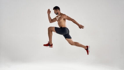 Young handsome caucasian male runner jumping high