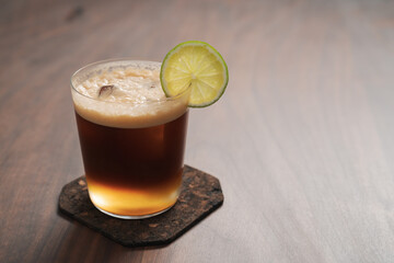 Espresso tonic in simple glass on walnut wood table with copy space