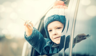 Little traveler. Boy looks out of the car window and holds a toy plane in his hand. Winter travel...