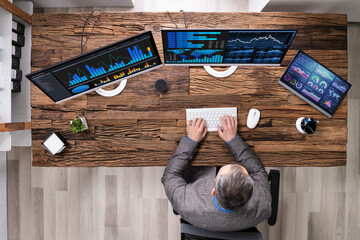 Analyst With Charts On Multiple Computer Screens