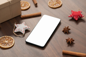 smarthone with white screen and christmas decorations on walnut table